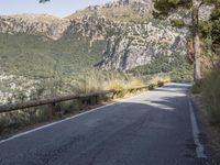 a paved road running beside a mountain on a sunny day in the mountains near marseille