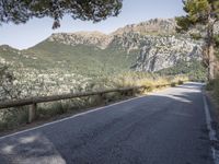 a paved road running beside a mountain on a sunny day in the mountains near marseille