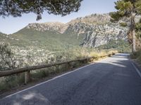 a paved road running beside a mountain on a sunny day in the mountains near marseille