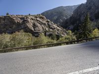 a person riding a skate board on a mountain road with a bike leaning against the railing