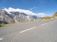 motorcycle parked on an empty road with a mountain range in the background with a road with white lines going down it