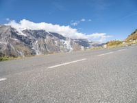 motorcycle parked on an empty road with a mountain range in the background with a road with white lines going down it