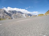 motorcycle parked on an empty road with a mountain range in the background with a road with white lines going down it