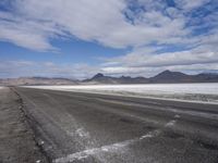 a lone, empty road leads through the desert landscape of the horizon line, with snow in the foreground