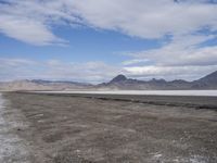 a lone, empty road leads through the desert landscape of the horizon line, with snow in the foreground