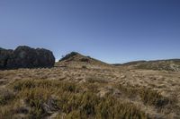 a mountain range that has two large rocks in the field and vegetation on top of it