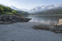 this is a river bed next to a lake in the mountains with trees and rocks on it