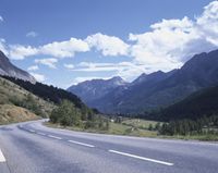 the highway is in the mountains and the hills are covered in green trees and grass