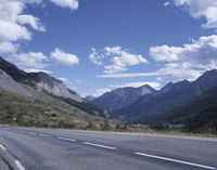 the highway is in the mountains and the hills are covered in green trees and grass