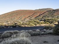 a lone motorcycle is parked on the road next to the hills of a mountain range