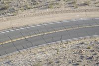 a motorcycle riding down a winding highway between hills and dry grass on a sunny day