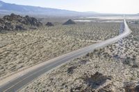 a motorcycle riding down a winding highway between hills and dry grass on a sunny day