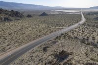 a motorcycle riding down a winding highway between hills and dry grass on a sunny day