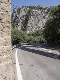 a person with backpack on the side of a road next to some trees and mountains