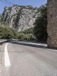 a person with backpack on the side of a road next to some trees and mountains