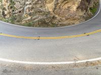 a person riding a motorcycle on a curved road with rocks in the background of their image