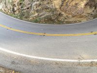 a person riding a motorcycle on a curved road with rocks in the background of their image