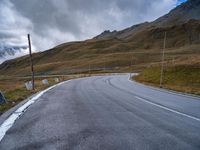 a mountain road leading to a very steep hill side with snow capped mountains in the distance