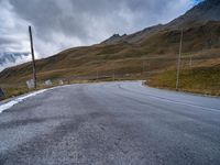 a mountain road leading to a very steep hill side with snow capped mountains in the distance