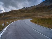 a mountain road leading to a very steep hill side with snow capped mountains in the distance