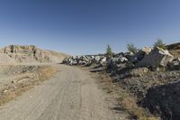 there is a bike rider on a paved dirt road through rocky area near a mountain