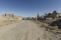 there is a bike rider on a paved dirt road through rocky area near a mountain