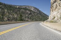 the view of a roadway in a mountainous area with high mountains and rocks below it