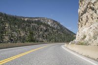 the view of a roadway in a mountainous area with high mountains and rocks below it