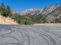 a mountain road with some cars driving down it and a few pine trees on the side