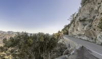 a curve road on a steep mountain side with pine trees at the side of it