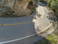 the curve on a winding road with trees in the background, and one person riding a motor bike on it