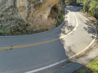 the curve on a winding road with trees in the background, and one person riding a motor bike on it