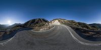 a long curved road going down a hill next to trees and bushes in the mountain