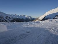 a skier stands on the slope in front of snowy mountains while it's not sunny