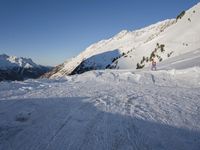 a skier stands on the slope in front of snowy mountains while it's not sunny