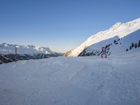 a skier stands on the slope in front of snowy mountains while it's not sunny