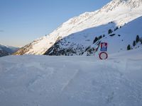 a skier stands on the slope in front of snowy mountains while it's not sunny