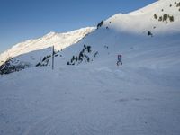 a skier stands on the slope in front of snowy mountains while it's not sunny