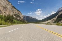 a single yellow line is on a highway that stretches into the mountains of canada and canada