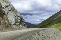 a truck driving down the side of a dirt road near a rocky outcrop