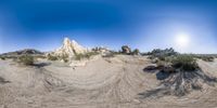 a 360 - camera view of a mountain in the desert, with a dog in the sand below it