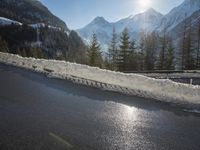 the snow is covering the road in the mountains with high peaks and evergreens in the distance