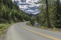 a scenic, mountain and tree - lined road on an island or land, with a yellow strip