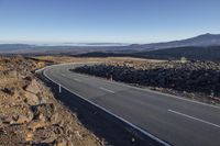 a road winding into the mountains with rocky terrain to either side of the road,