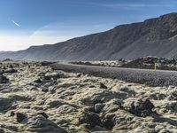 the large mountains are covered in moss and rocks with a road winding down one side