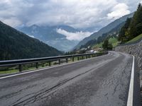 a road surrounded by mountains and tall trees with a cloudy sky above it below,