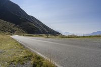 a motorcycle rides on the side of a winding road in the mountains overlooking a valley