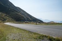 a motorcycle rides on the side of a winding road in the mountains overlooking a valley