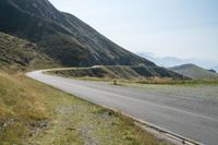 a motorcycle rides on the side of a winding road in the mountains overlooking a valley