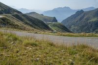 a motorcycle parked on a small mountain side road near mountains with no cars driving on it